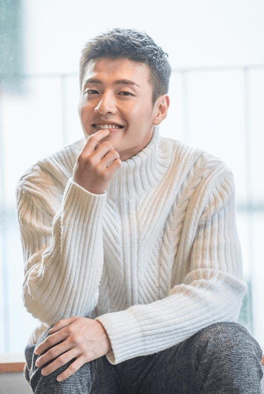 白いタートルニットを着て微笑む韓国の俳優カンハヌル